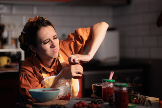 Frustrated Housewife Struggling To Open Tight Jar Lid In Kitchen. Stressed young woman using maximum effort trying to open stubborn homemade jam jar