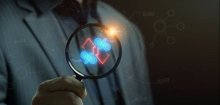 Close-up shot of hand holding magnifying glass to inspect glowing percentage icon with Quality up and Cost down indicators. Business cost reduction and quality optimization inspection concept.