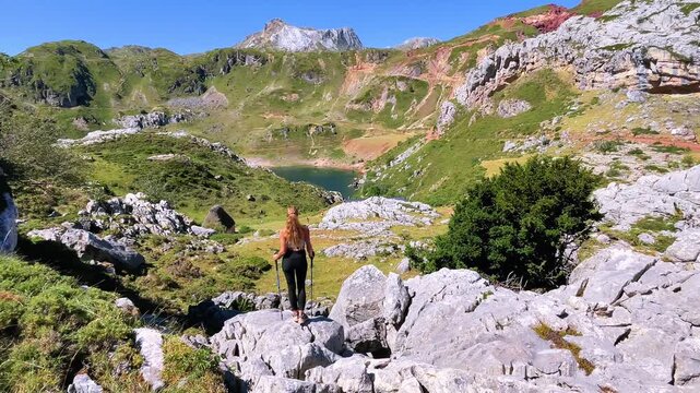 young woman hiking in mountains looking at lake landscape, Somiedo in Spain