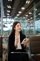 Obraz premium Airport phone travel woman using mobile phone in business class lounge waiting for plane flight texting sms message on smartphone. Technology and travel people frequent flying lifestyle.