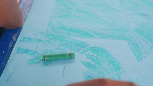 Mother and child finishing crayon artwork on blue paper, crayon resting on page, loose teal sketches and textures, childs hand moving away, quiet proud moment, keepsake memory of play