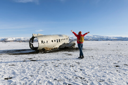 A tourist  woman  walking on the crashed plane on the frozen Solheimasandur beach in winter in Iceland