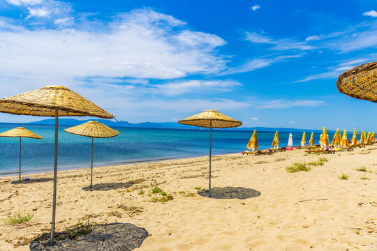 Sunny beach near cunda island on the aegean coast in turkey with straw umbrellas and turquoise sea. Travel, relaxation and summer vacation concept.