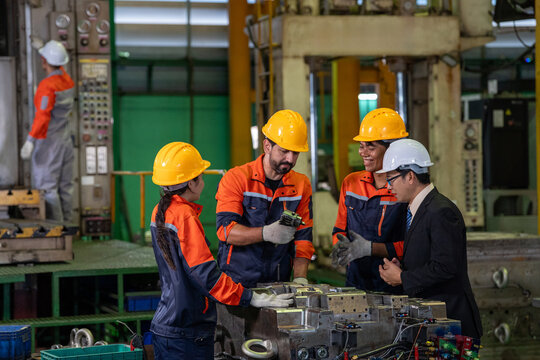 Factory engineer team safety helmet, industrial worker group inspecting metal mold machinery on manufacturing floor