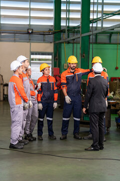 Engineer factory worker helmet safety team industry uniform manager group meeting on production floor with machinery