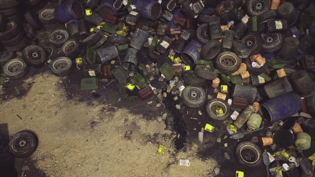 Debris field of tires and packaging strewn across wet sand, bright labels and scattered materials create aftermath scene requiring cleanup.