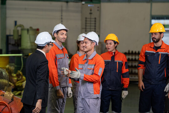 Engineer factory worker hard hat safety team industrial uniform, group meeting on factory floor with machinery