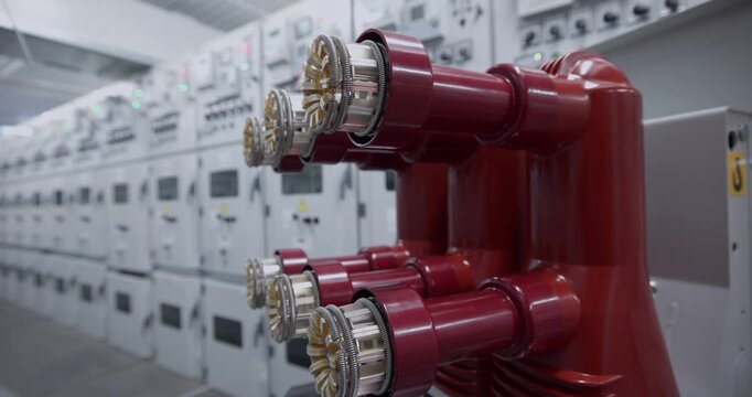 Red high voltage electrical connectors mounted on switchgear in industrial substation interior.