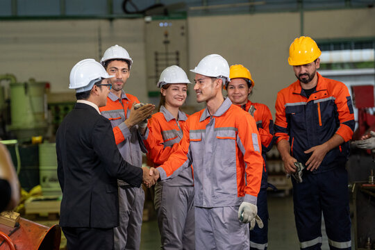 Engineer factory worker hardhat handshake safety team industry uniform group in workshop during industrial meeting