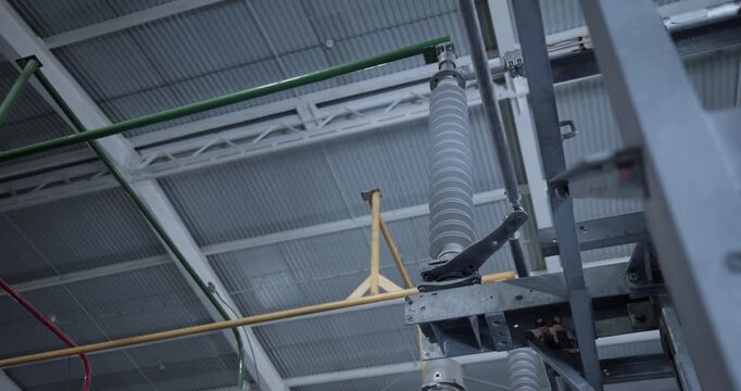 Inspection of high voltage insulator and overhead conduits inside industrial warehouse.