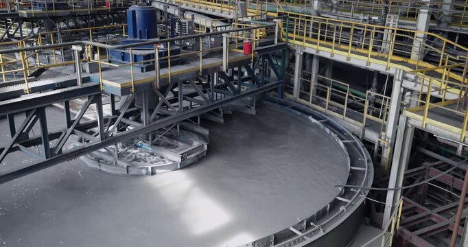 Flotation and processing circular clarifier tank for iron production from ore on mining factory. Closeup of fine pulp with bubbles, concentration industry plant.