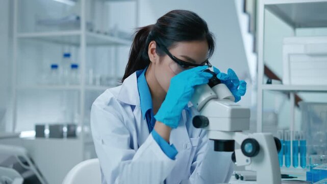Asian Researcher using a microscope in the clinical lab.Female Researcher working in the clinical laboratory,Medical or scientific researcher or Asian woman doctor looking at professional microscope.

