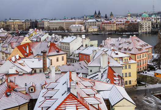 Snow-covered rooftops and Prague skyline across the Vltava River in winter