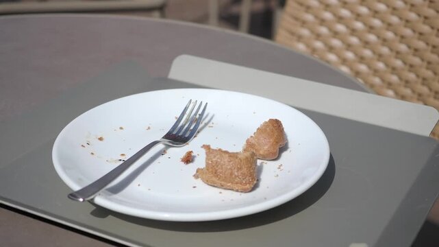Empty plate and fork at an outdoor cafe table