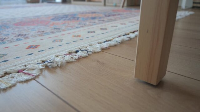 Table leg on wooden floor near rug in home environment