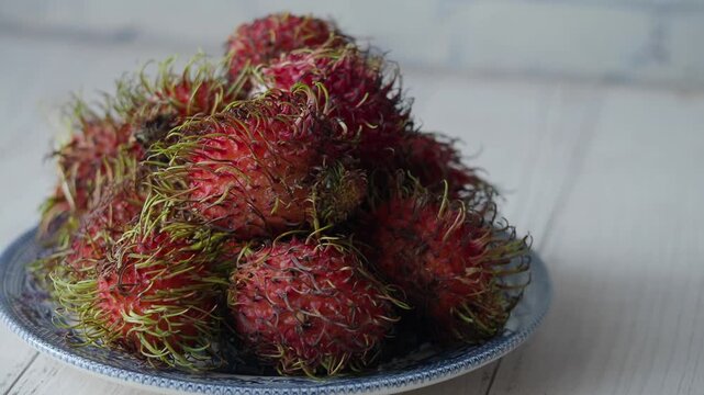 Rambutan fruit displayed on a plate in a bright space