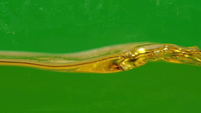 Golden liquid oil wave flowing smoothly against a vibrant green background in motion