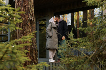 Fototapeta premium Couple sharing a kiss in a cozy forest cabin setting during a calm autumn afternoon