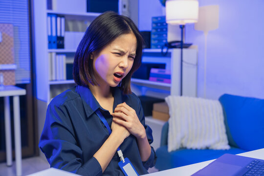 Young Asian businesswoman experiencing chest pain while working in office, health problem and workplace stress concept