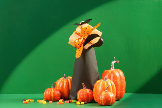 Halloween gift box in shopping bag with pumpkins and candy on green background