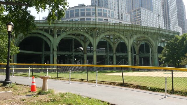 New York City, Manhattan, United States of America. Riverside Park South. Miller highway remnant, elevated viaduct in Upper West Side. Green arch of overpass bridge ruins near baseball sport field.