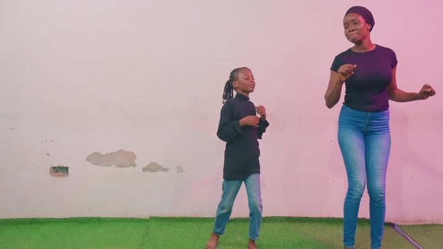 Guided dance practice on grassy area. Mother and child engaged in coordinated dance training outside. Nurturing mother patiently guides her child through dance routine outdoors in grassy area