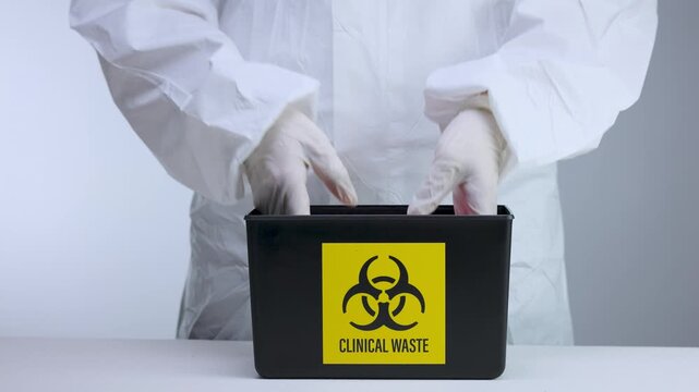 Cautious medical worker handling clinical waste management inside sterile laboratory using biohazard container safety glove
