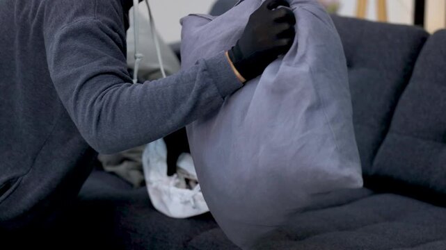 Masked Burglar in Black Gloves Searching Sofa for Stolen Cash and Loot