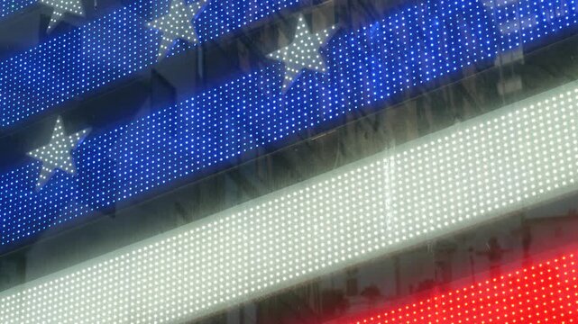 American flag on Broadway, Times Square in New York City, United States. Electric lights glowing. Symbol of democracy, national attribute of USA. 4th July or 911 September 11 concept. Military Island.
