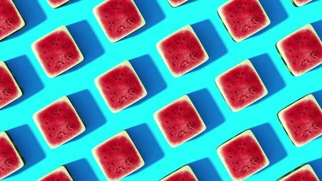 Top view of repeated square watermelon slices casting sharp shadows on a vivid blue background as the geometric summer pattern slowly rotates in loop 3d animation