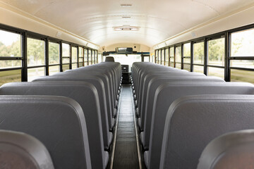 Fototapeta premium Interior of school bus with empty seats and bright interior lighting. School bus features spacious layout with rows of seats and clear windows for a bright atmosphere.
