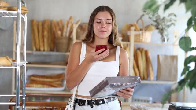 Young woman checks calorie content of cookies in box using app on phone