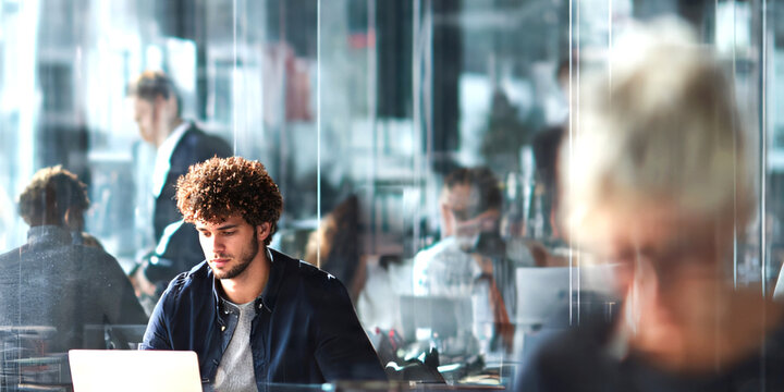 A young businessman work diligently in a busy office.