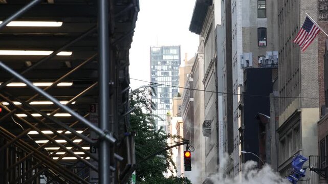 New York City Downtown or Midtown urban buildings architecture, Manhattan street, United States of America. Hot steam smoke vapor. Sidewalk pavement scaffolding, construction maintenance. USA flag.