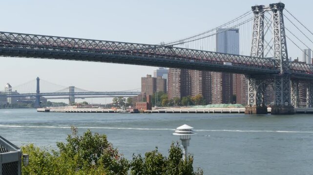 Williamsburg Bridge in Brooklyn, New York City, United States. Transport metallic bridge over East River water near Marcy Av subway station and Domino park in Williamsburg. Riverfront elevated walkway