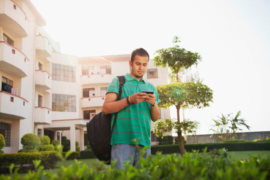 College student reading sms on mobile phone