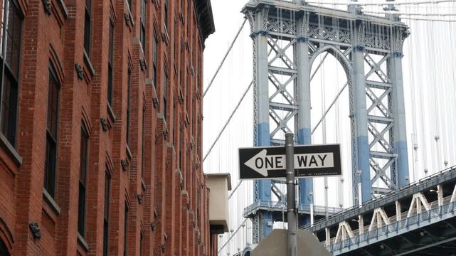 Manhattan bridge in Brooklyn Dumbo, New York City, United States of America. Red brick building architecture, windows on Washington street. Tourist landmark in NYC, USA. One way road sign.