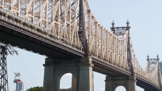 New York City Manhattan Midtown, Queensboro bridge architecture in United States. Urban public transport, tramway to Roosevelt island over East River. Red tram cabin car. Metallic bridge in East Side.