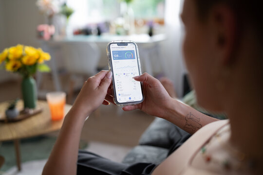 A white woman checks her glucose levels on a health app while at home