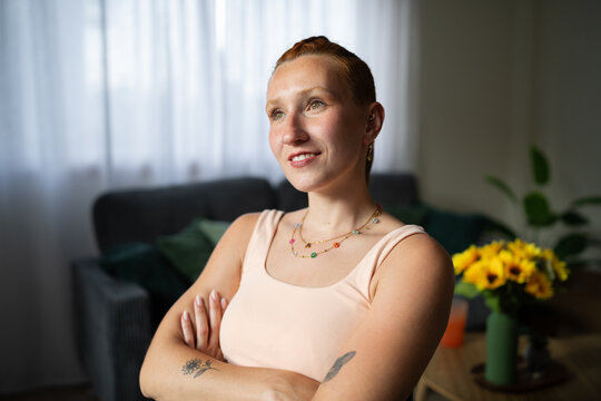 A white woman poses with crossed arms smiling indoors