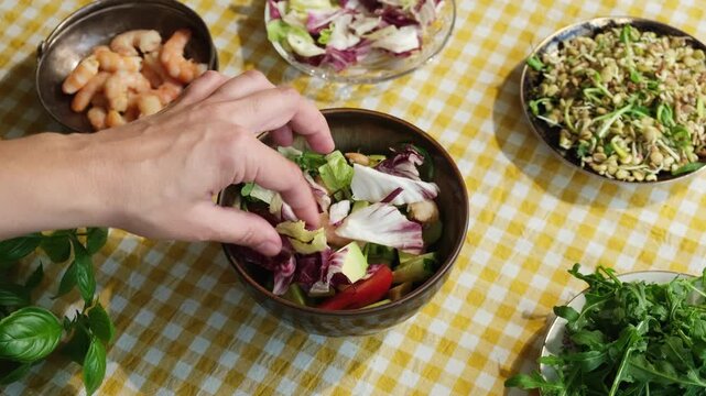Woman making summer salad with shrimps, avocado and greens. Preparing healthy dinner