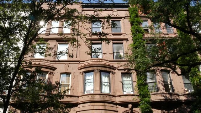 New York City townhouse buildings, brownstone row houses in Manhattan or Brooklyn, United States of America. Classic buildings on residential district street. Real estate property. Rowhouse townhome.