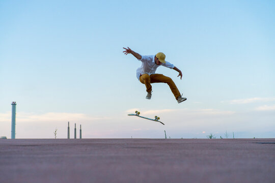 Young man doing a skateboard trick on a lane at dusk