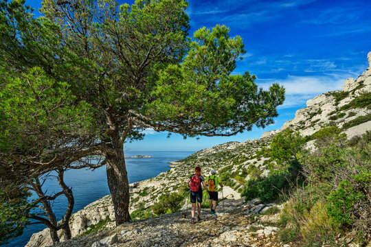 Man and woman hike a rocky coastal trail in Calanques France