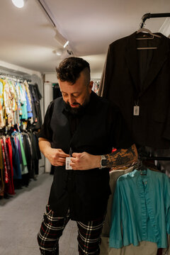 Man with beard tries on black vest in vintage clothing store