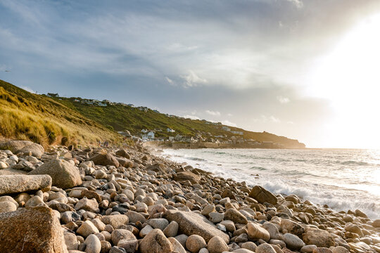Sunlight illuminates the rocky beach at Whitesand Bay in Cornwall