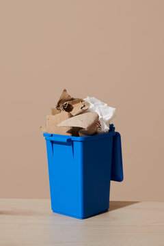 Blue recycling bin with paper and cardboard waste on tabletop