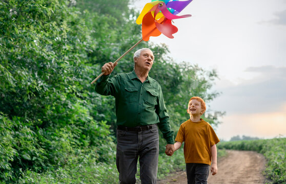 Grandfather and grandson hold a pinwheel on a rural dirt road