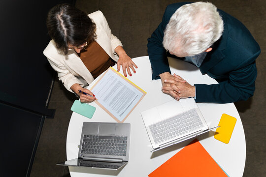 Businesswoman and businessman read document at the office