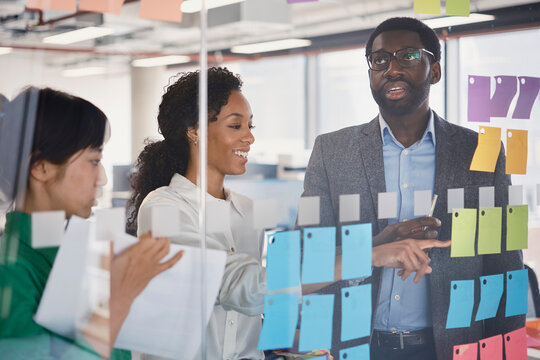 Colleagues discuss business strategy on a glass wall in London